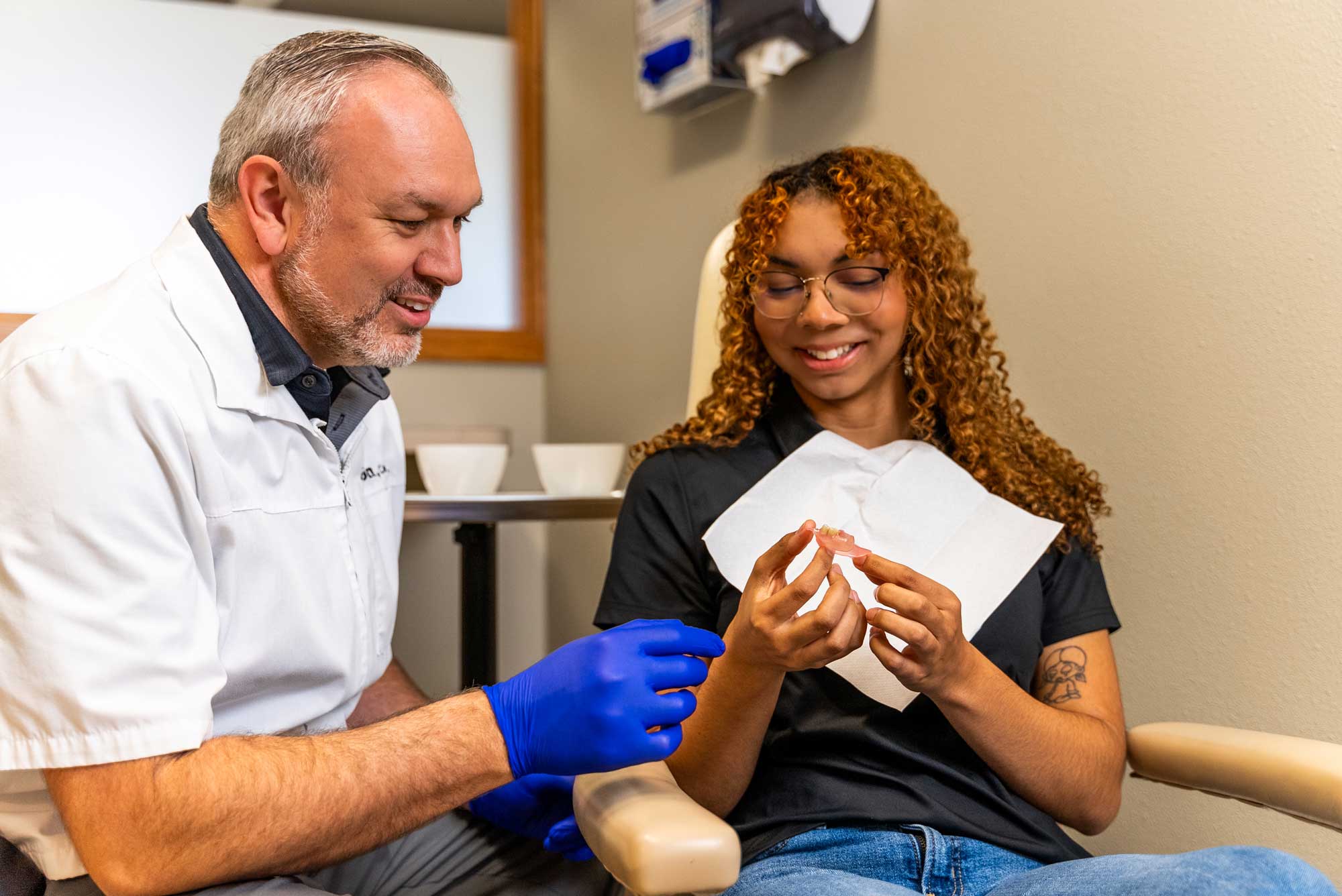Denturist-patient patient looking at denture